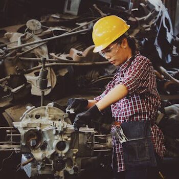 pexels-photo-1108101-1108101 Woman engineer wearing safety gear, working on machine repair in an industrial setting.
